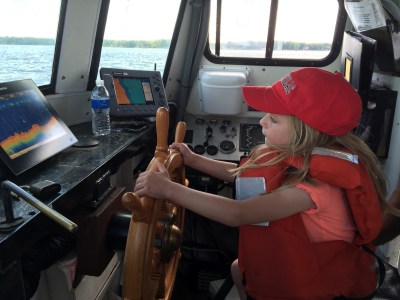 young girl driving boat during charter tour