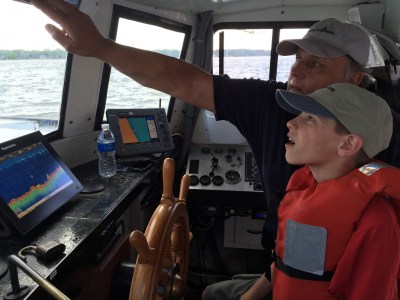 young man being shown around boat navigation during charter tour