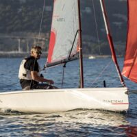 one person manning a Beneteau First 14 sailboat on the water