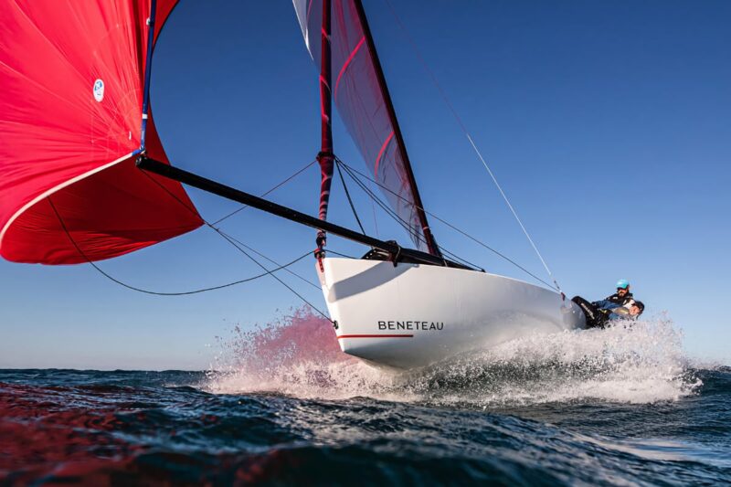 Beneteau First 18 SE sailboat with red sail hitting waves