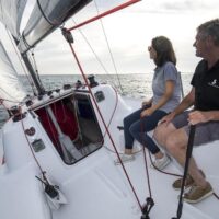 two people sitting on side of a Beneteau First 24 sailboat