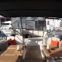 Beneteau Oceanis Yacht 62 deck table and seating area shaded by canopy and other docked boats