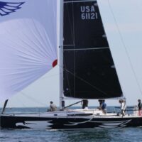 J Boats J/121 with small black sail and large white sail in open waters