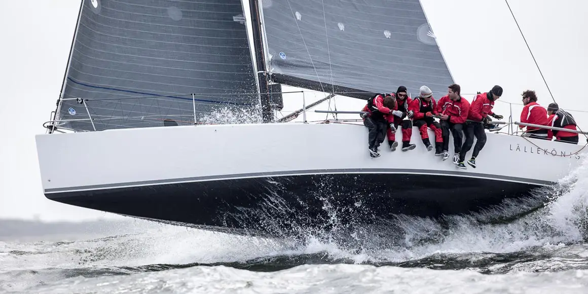 Seven men in red and black on a J-Boat J/111 sailboat.