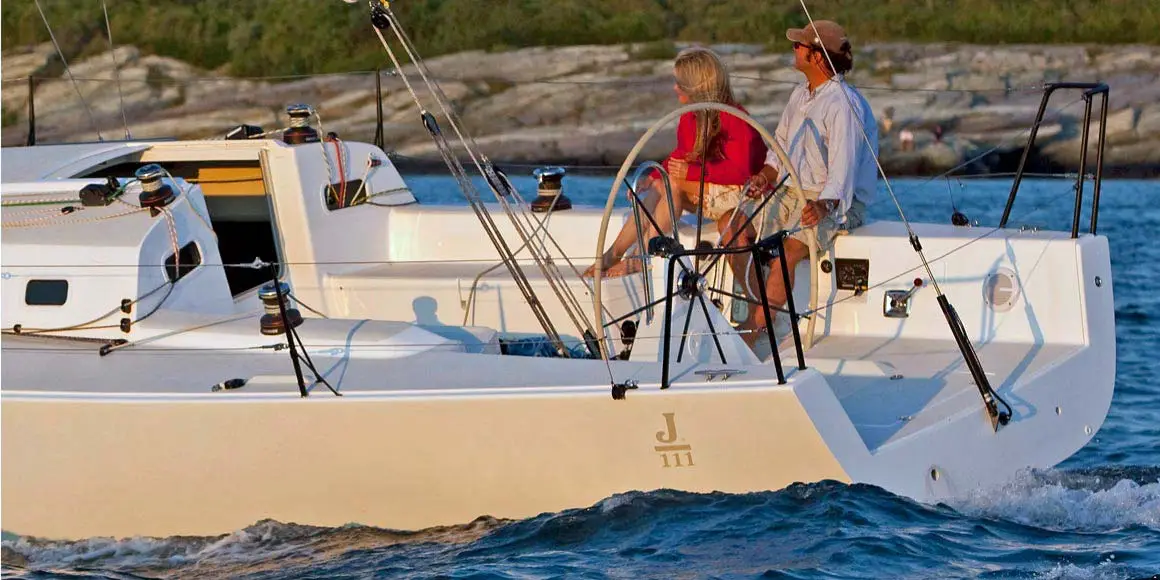 Couple leisurely sailing a J-Boat J/111 sailboat near shore.