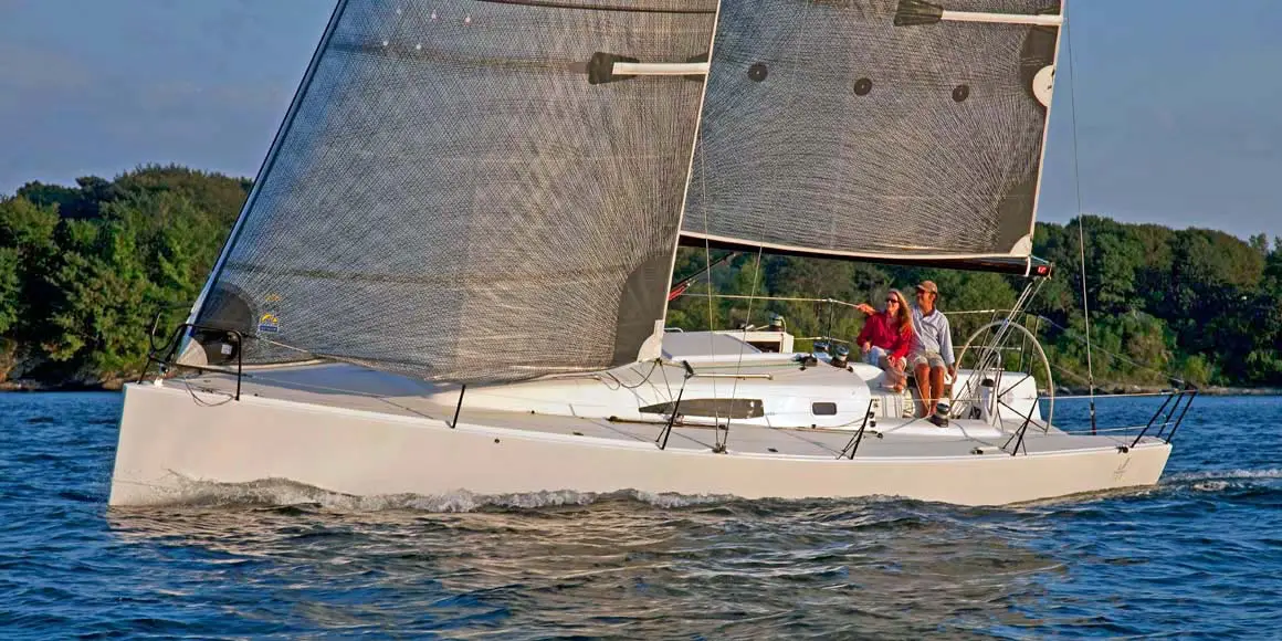 Couple leisurely sailing a J-Boat J/111 sailboat near shore.