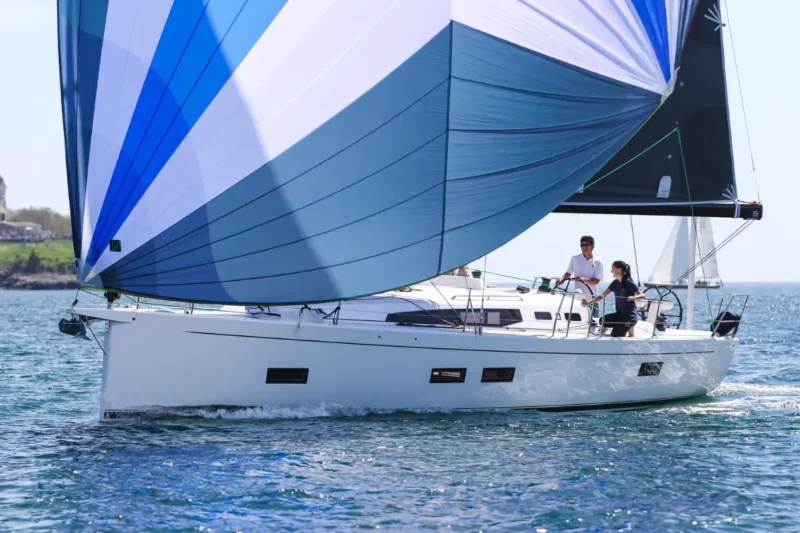 Couple sailing on a J-Boat J-40 sailboat with blue and white sail.