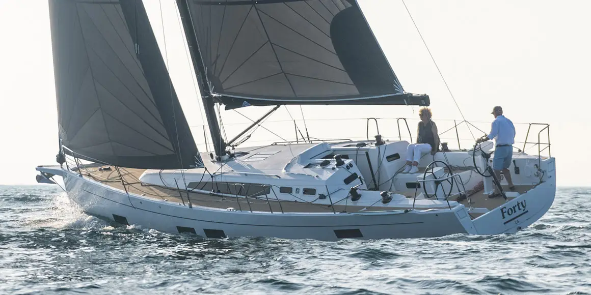 Two older people sailing a J-Boat J-40 sailboat.