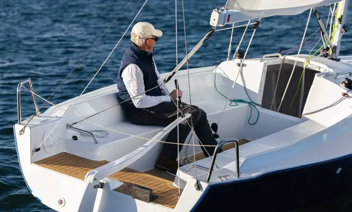 Older man sitting in the cockpit of a J-Boat J-7 sailboat.