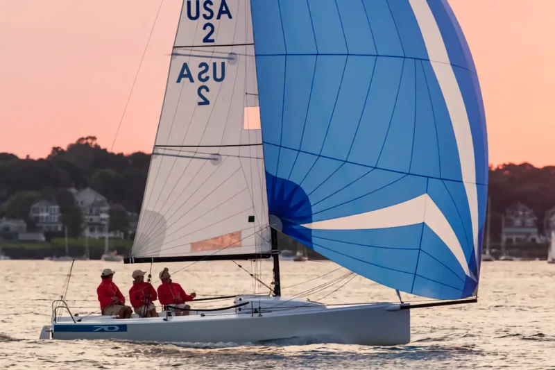 J-Boat J70 sailboat with three-man crew at sunset.