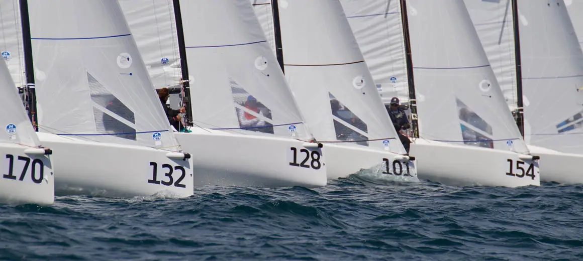 Lineup of J-Boat J70 sailboats during a race.