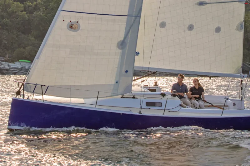 Two people sailing a J-Boat J/9 sailboat during sunset.