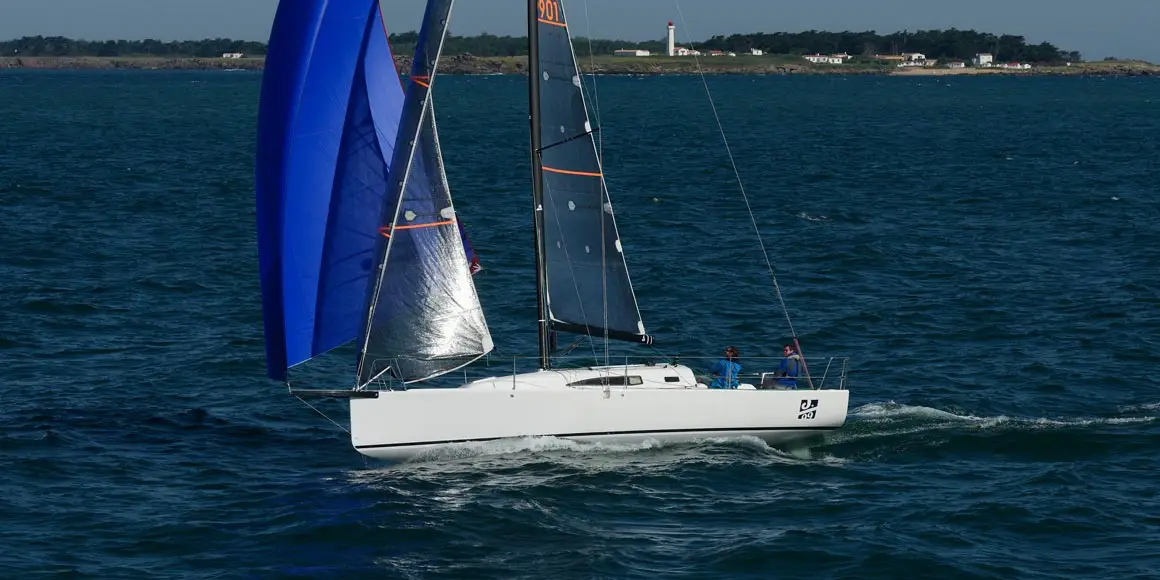 Two person crew sailing a J-Boat J99 sailboat with blue and black sails.