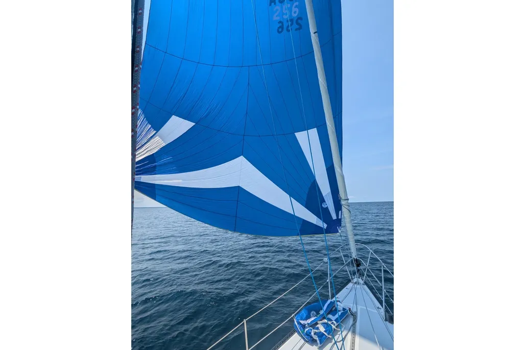 Looking out over the bow of a 1984 Catalina 38 sailboat with a blue sail on open water.